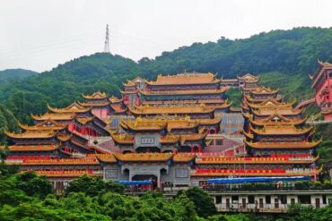 Dalingshan,Dongguan,Chinatour Multi-tiered Chinese temple complex with golden roofs perched on a green hillside atop the hill.
