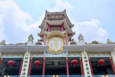 Shangxiajiu Pedestrian Street,Guangzhou,Chinatour Front view of a Chinese temple with red columns, gold ornamentation, and red lanterns against a blue sky.