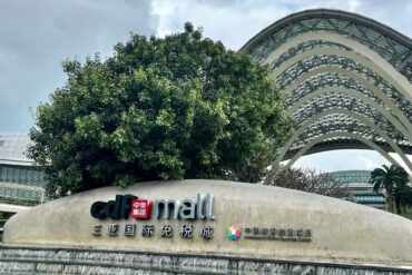 Facade sign reading 'cdf mall' with Chinese characters, a large tree behind, and curved glass arches in the background.