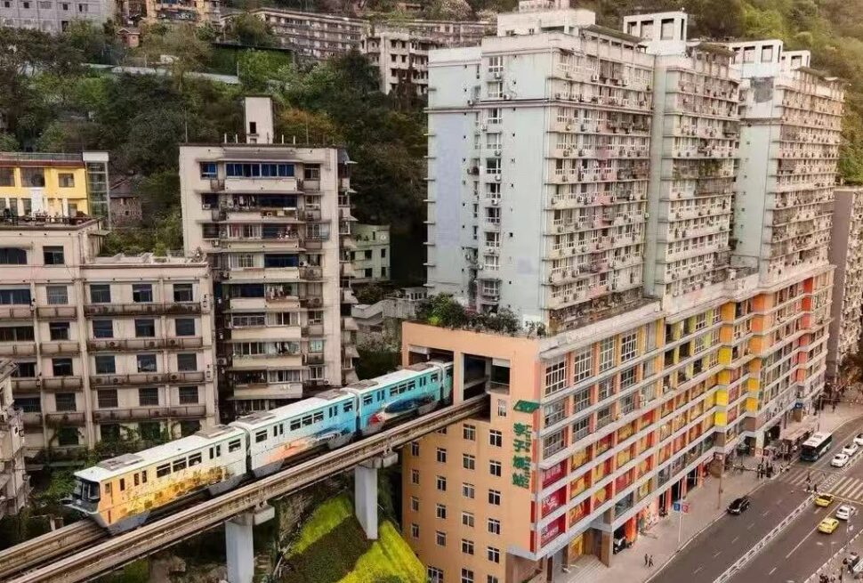 Liziba Station,Chongqing,Chinatour Elevated metro train passing between colorful high-rise buildings on a hillside city street.