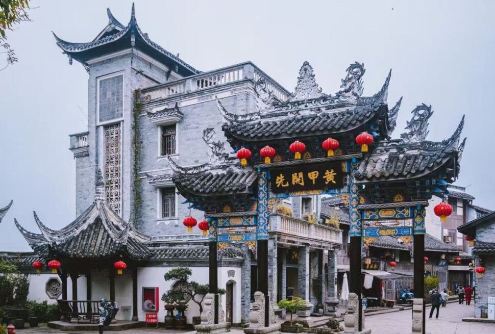 Tongliang Ancient Town,Chongqing,Chinatour Ornate Chinese paifang arch with blue-gold detailing and red lanterns in a temple courtyard