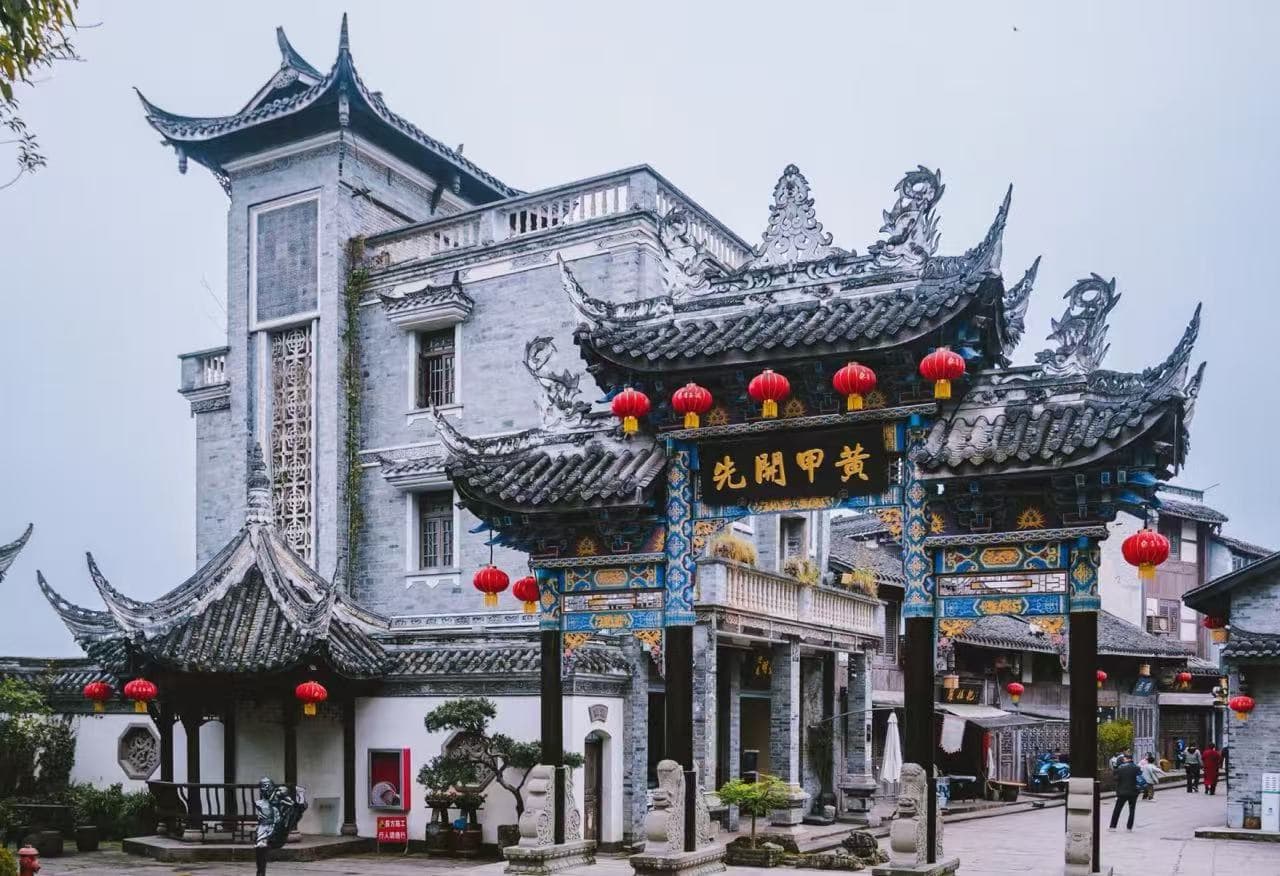 Tongliang Ancient Town,Chongqing,Chinatour Ornate Chinese paifang arch with blue-gold detailing and red lanterns in a temple courtyard