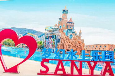 Sanya Fantasy Water World,Sanya,Chinatour A bright water park entrance with a large pink heart sculpture and blue sign reading 梦幻水上乐园 SANYA against a castle backdrop.