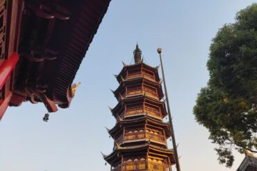 Suzhou Nanchan Temple and Ancient Town,Suzhou,Chinatour Six-story Chinese pagoda with red wooden eaves rising beside a tree, under a clear sky (temple complex).