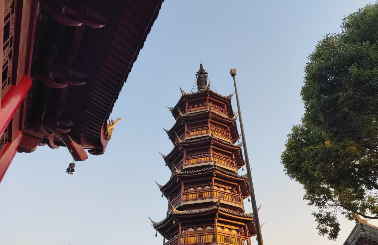 Suzhou Nanchan Temple and Ancient Town,Suzhou,Chinatour Six-story Chinese pagoda with red wooden eaves rising beside a tree, under a clear sky (temple complex).