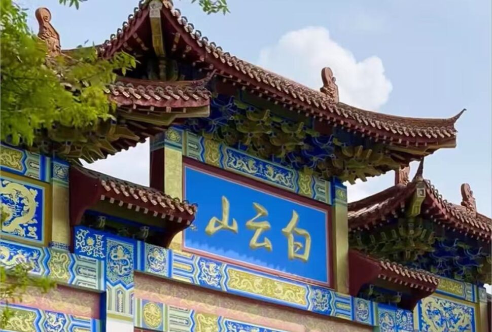 Baiyun Mountain,Guangzhou,Chinatour Ornate Chinese temple gate with a blue plaque bearing gold Chinese characters and decorative blue-yellow patterns under a tiled red roof.