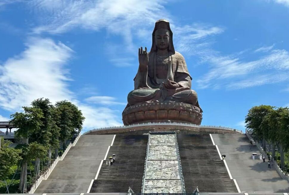 Xiqiao Mountain,Foshan,Chinatour Giant seated statue of Guanyin atop a wide stone staircase under a blue sky.