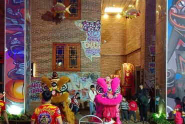 Leizhou Ancient City,Leizhou,Chinatour Two colorful lion dance costumes (pink and brown) performing in a brick-walled alley while children watch nearby.