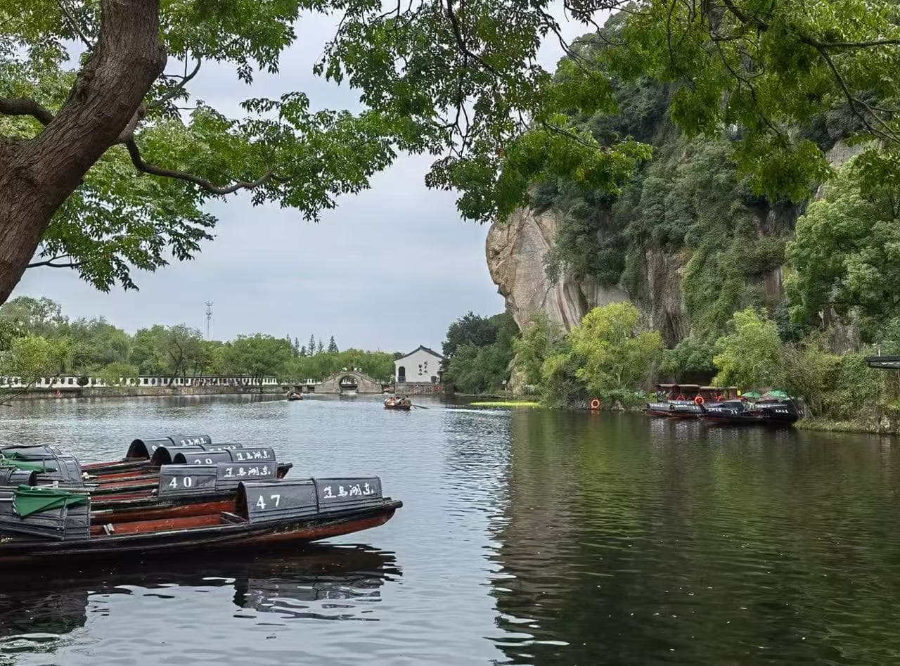 Rowboats numbered 40–47 docked along a calm river with green trees and a rocky cliff in the background.