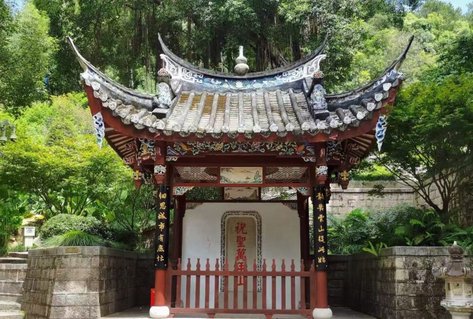 Drum Mountain Scenic Area,Fuzhou,Chinatour Traditional Chinese pavilion with a curved tiled roof and red wooden pillars set in a lush garden. (Informative, scene-setting)