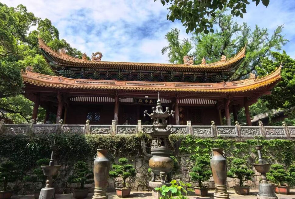 Fayu Temple,Zhoushan,Chinatour Traditional Chinese temple with a curved, ornate roof, stone railing, and surrounding trees in a tranquil courtyard.