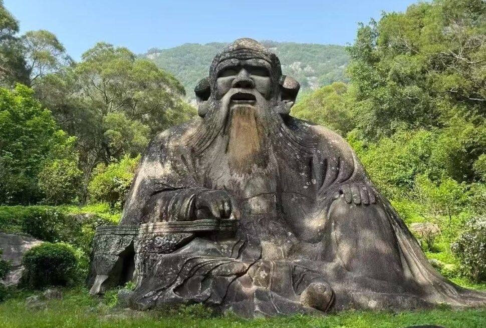 Mount Qingyuan Scenic Area,Quanzhou,Chinatour Large stone statue of a seated ancient sage with a long beard in a lush garden/park setting.