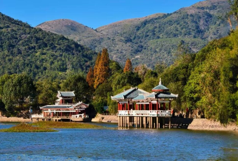 Traditional Chinese pavilions on a wooden jetty over a calm lake, with green hills and blue sky in the background,Jiuli Lake,Putian,Fujian,Chinatravel