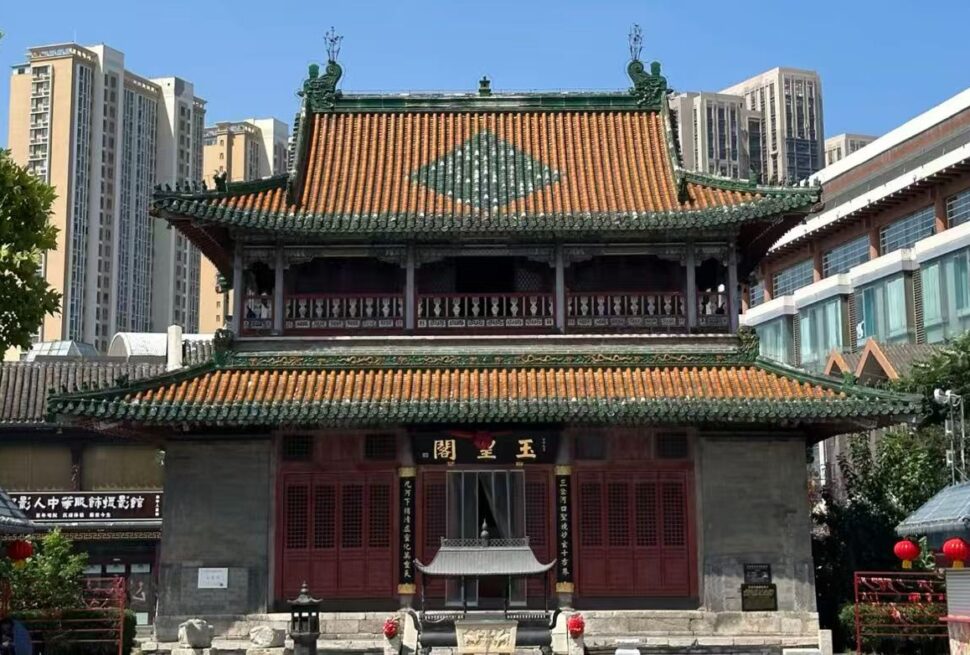 Tianhou Palace ,Tianjin,Chinatour Traditional Chinese temple with red doors and ornate green-tiled roof, set against modern high-rises in an urban plaza.
