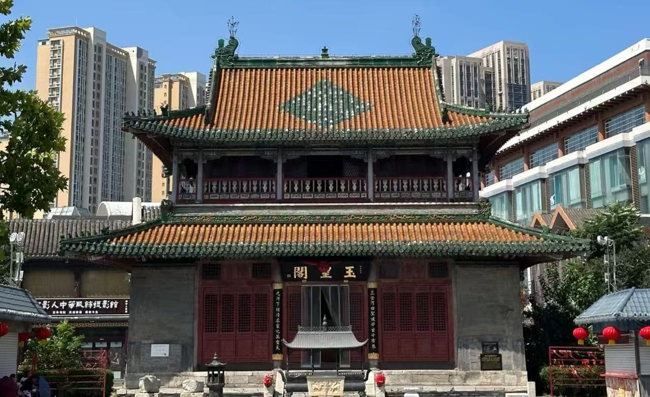 Tianhou Palace ,Tianjin,Chinatour Traditional Chinese temple with red doors and ornate green-tiled roof, set against modern high-rises in an urban plaza.