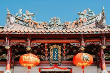 Tianhou Temple,Quanzhou,Chinatour Entrance of a traditional Chinese temple with an ornate dragon-adorned roof, red columns, and two red lanterns; plaque reads 天后宮.