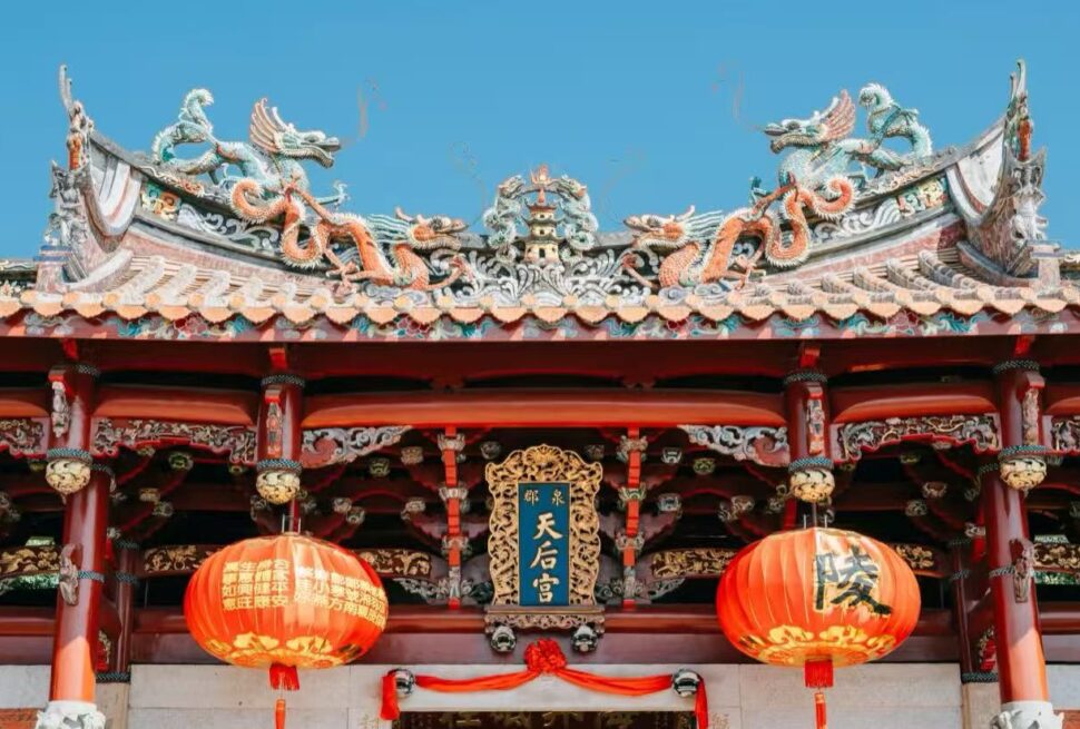 Tianhou Temple,Quanzhou,Chinatour Entrance of a traditional Chinese temple with an ornate dragon-adorned roof, red columns, and two red lanterns; plaque reads 天后宮.
