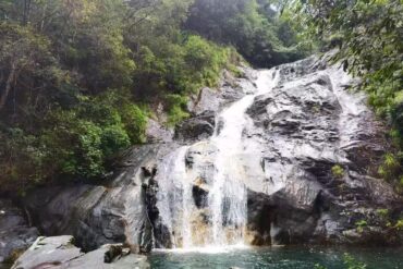 Huayan National Forest Park,Wenzhou,Chinatour Waterfall cascading down gray rocks into a tranquil pool, surrounded by dense green forest.