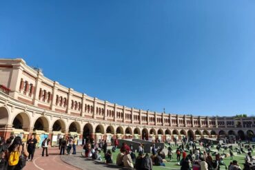 Tianjin Five Great Avenues Wudadao,Tianjin,Chinatour Curved cream-colored arcade with arches surrounds a grassy plaza where people sit and chat on a sunny day.