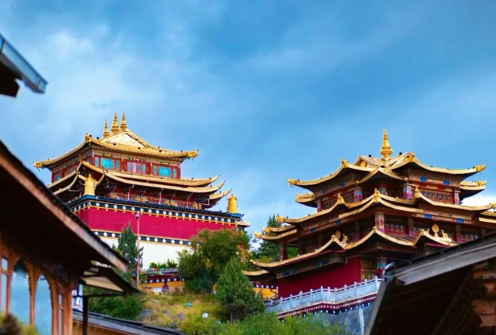 Traditional temple complex with gold-topped pagodas and red walls under a blue sky.Dukezong Ancient Town,Shangri-La,Yunnan,Chinatravel