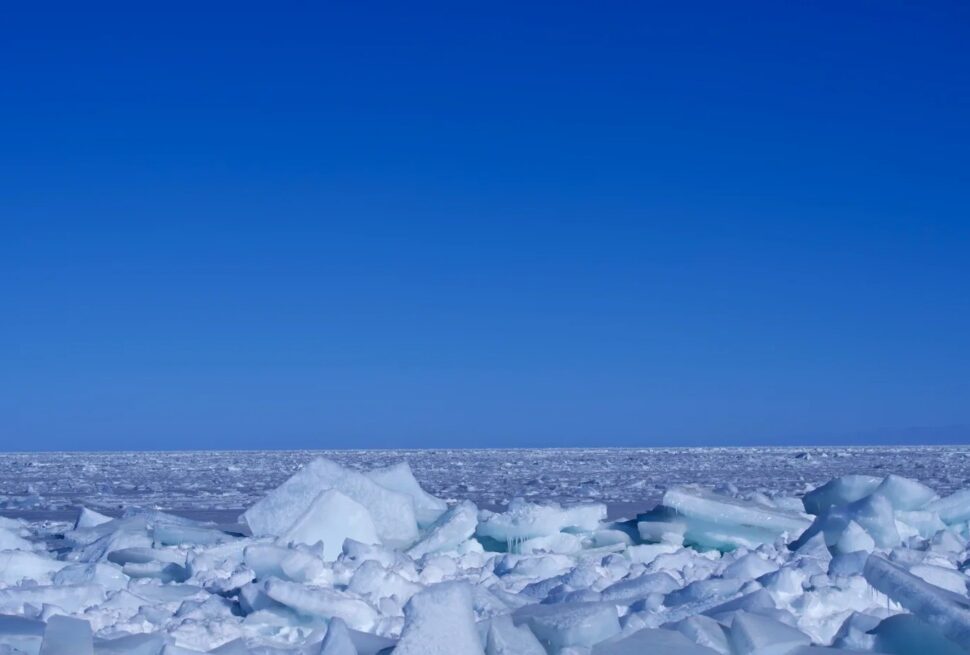 Ice-covered shore with jagged white ice chunks under a clear blue sky, Arctic horizon in the distance.Qinghai Lake,Xining,Qinghai