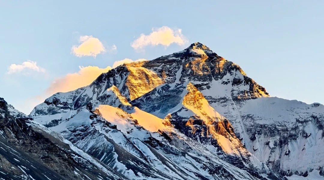 Snow-capped mountain peak bathed in warm sunset light against a clear blue sky.Mount Everest Base Camp,Lhasa,Tibet,Chinatravel