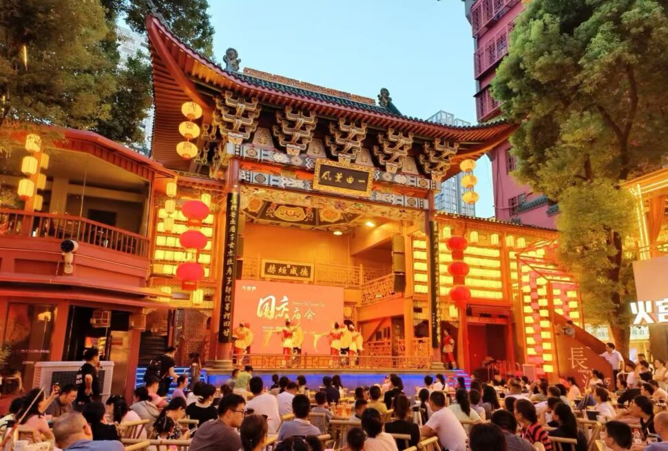 Outdoor Chinese cultural stage under a ornate temple gate with red lanterns, large audience watching a performance at dusk/evening.Huangxing Road Pedestrian Street,Changsha,Hunan ,Chinatravel