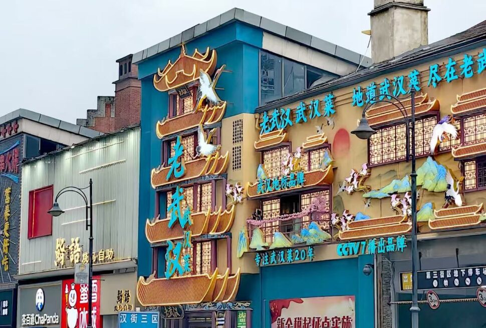 Colorful Chinese restaurant facade with vertical neon blue characters and ornamental orange river boat shapes along the building edge.Han Street Pedestrian Zone,Wuhan,Hubei ,Chinatravel