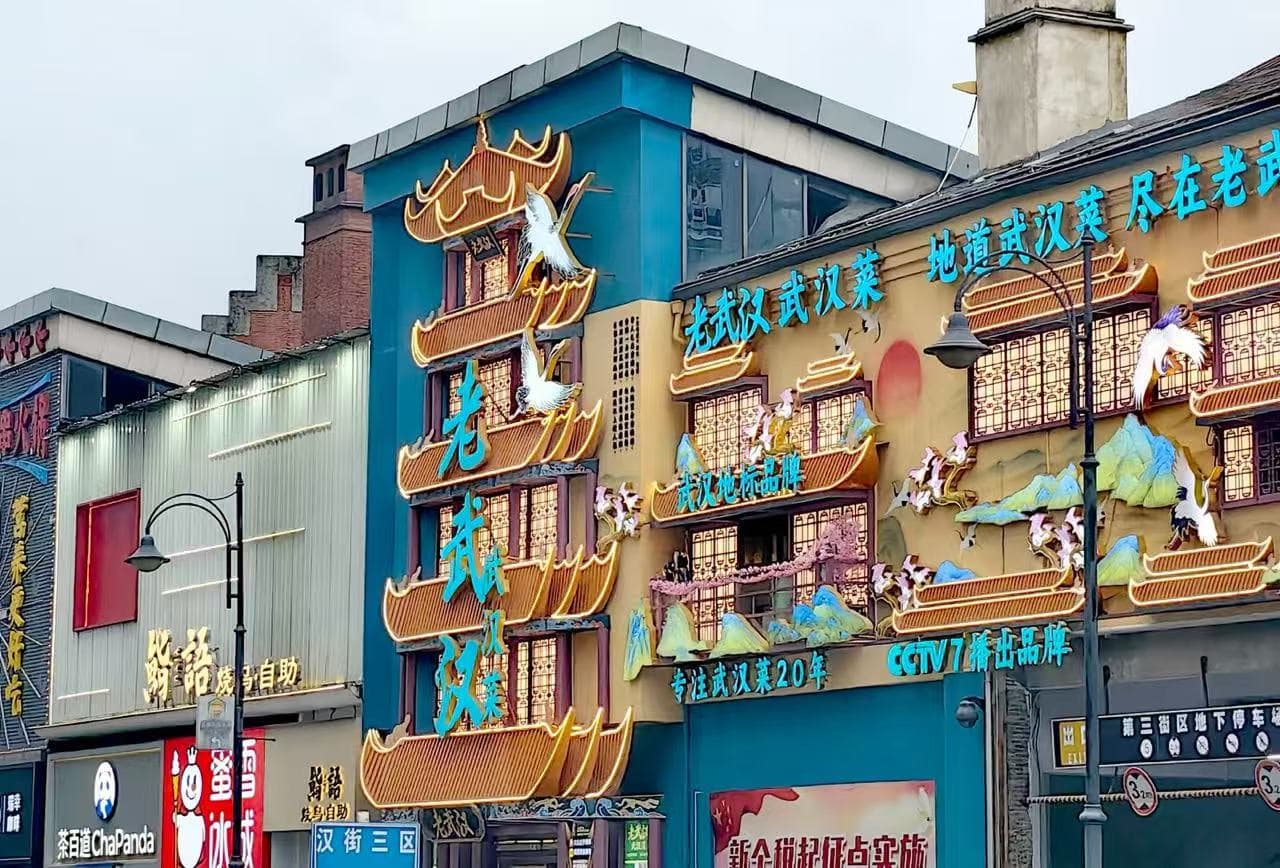 Colorful Chinese restaurant facade with vertical neon blue characters and ornamental orange river boat shapes along the building edge.Han Street Pedestrian Zone,Wuhan,Hubei ,Chinatravel