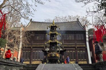 Traditional Chinese temple with a tall tiered incense burner in front and red ribbons hanging from trees in the courtyard.Changchun Guan Taoist Temple,Wuhan,Hubei ,Chinatravel