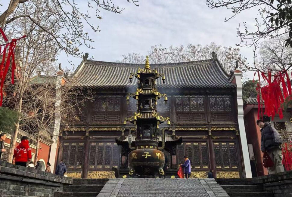 Traditional Chinese temple with a tall tiered incense burner in front and red ribbons hanging from trees in the courtyard.Changchun Guan Taoist Temple,Wuhan,Hubei ,Chinatravel