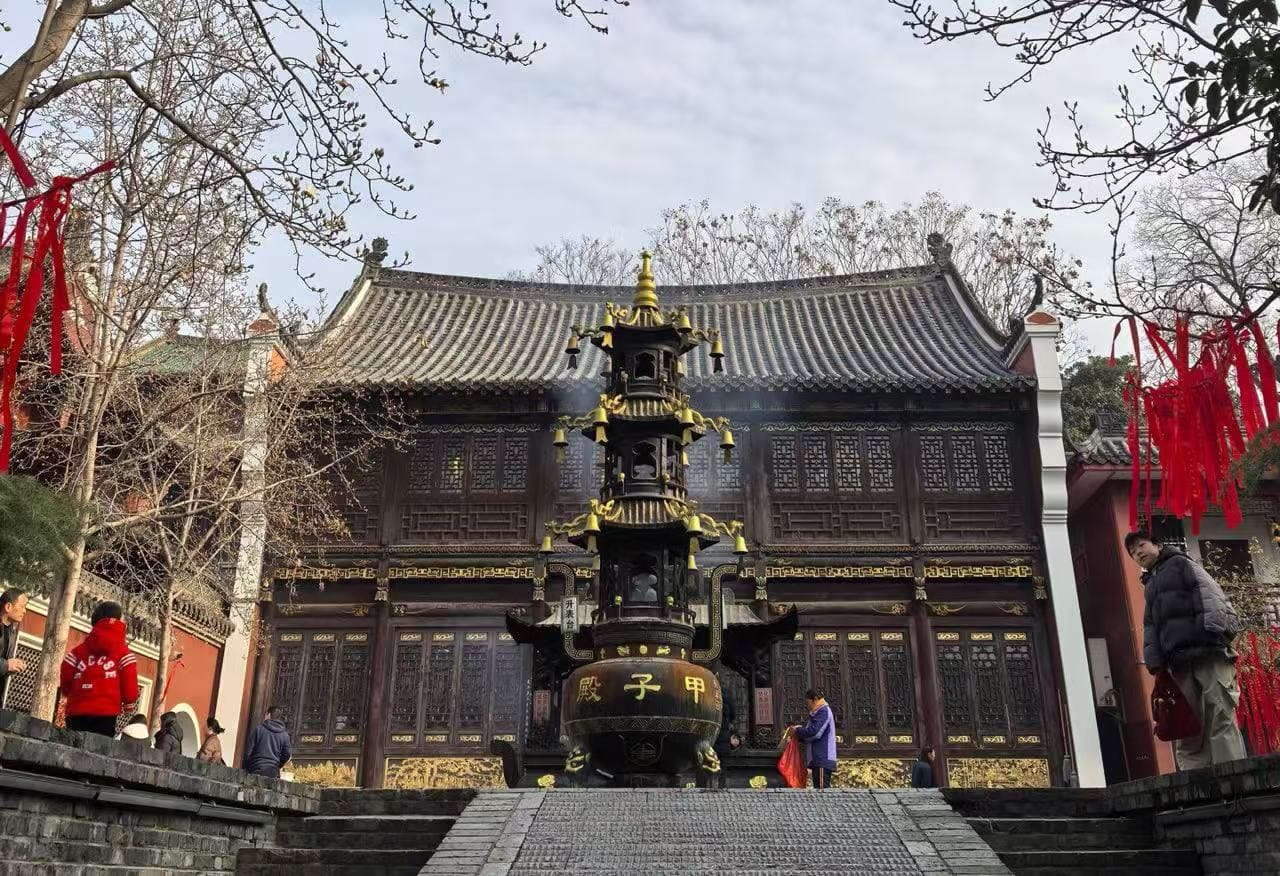 Traditional Chinese temple with a tall tiered incense burner in front and red ribbons hanging from trees in the courtyard.Changchun Guan Taoist Temple,Wuhan,Hubei ,Chinatravel