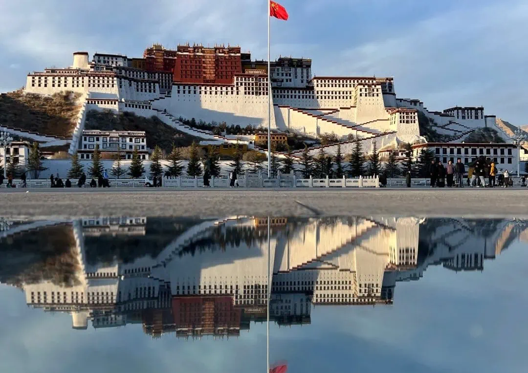 Potala Palace perched on a hill with a red flag, reflected in a calm water surface below,Potala Palace,Lhasa,Tibet,Chinatravel