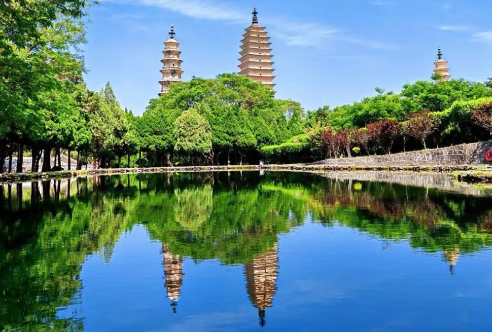Three-tiered pagodas rise above a green park, reflected in a calm lake.Dali Three Pagodas,Dali,Yunnan,Chinatravel