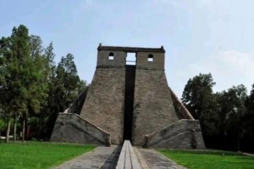 Stone pyramid-like monument with two flared staircases on either side and a central vertical opening, set in a green park with trees in the background.Star Observatory,Shaolin & Songshan Area,Henan,Chinatravel