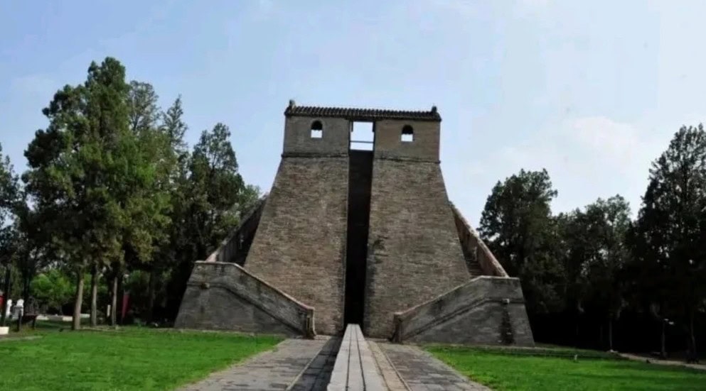Stone pyramid-like monument with two flared staircases on either side and a central vertical opening, set in a green park with trees in the background.Star Observatory,Shaolin & Songshan Area,Henan,Chinatravel
