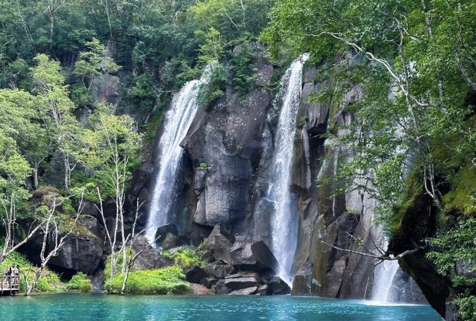 Baishan North Slope Scenic Area,Baishan,Jilin,Chinatravel Waterfall cascade over rocky cliff into a turquoise lake surrounded by green trees.