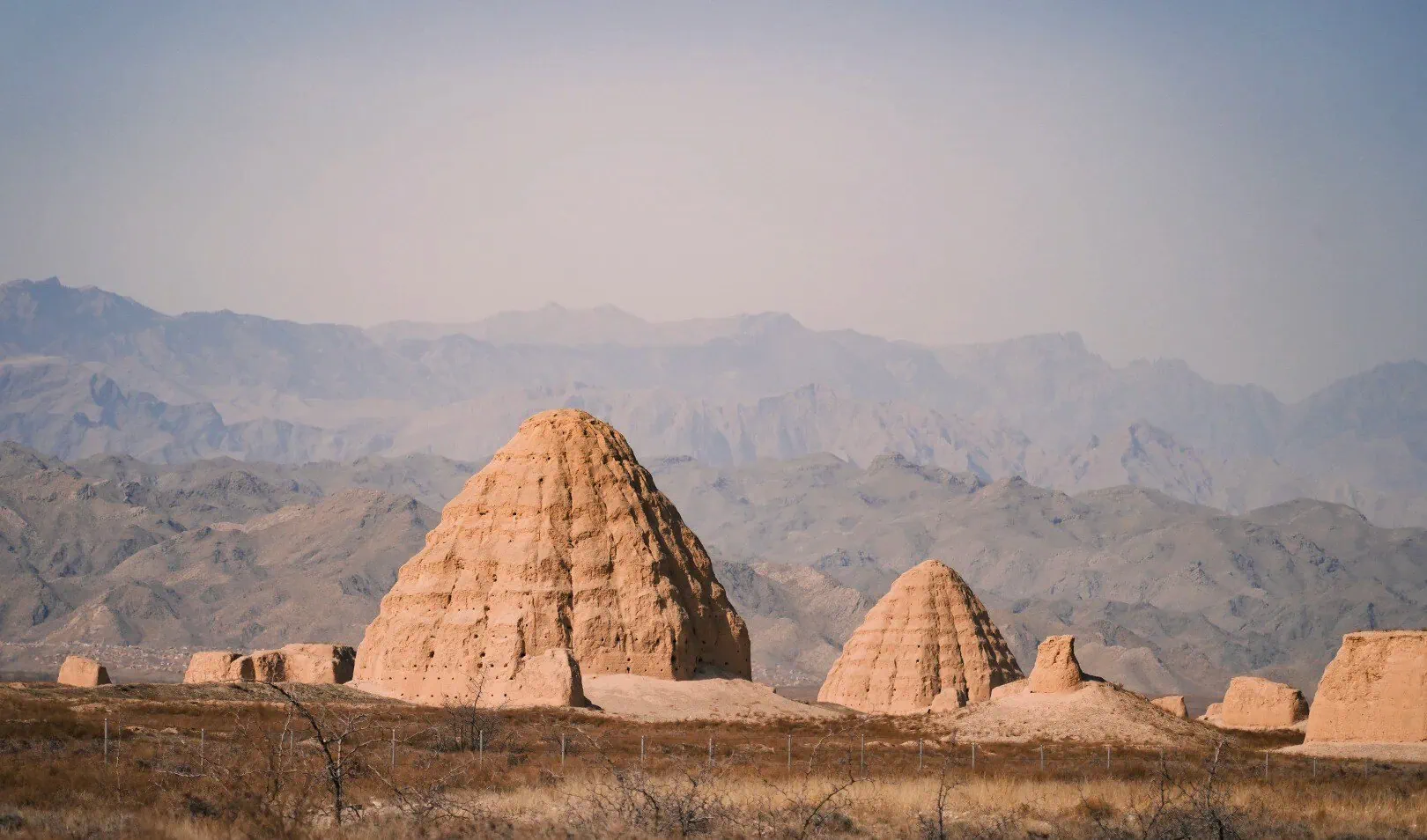 Western Xia Imperial Tombs,Yinchuan,Ningxia,Chinatravel Desert landscape with large earthen pyramidal structures in the foreground and distant mountains on the horizon.