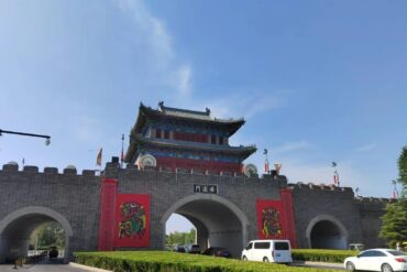 Kaifeng Ancient City Wall,Kaifeng,Henan,Chinatravel Traditional Chinese city gate with a multi-tier pagoda on top, gray brick walls, red banners, and arched entryways.
