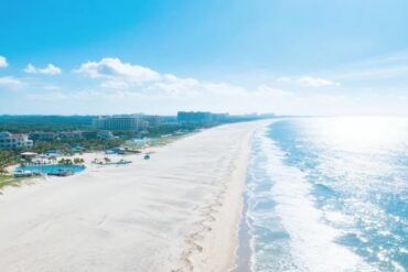 Silver Beach,Beiahi,Guangxi,Chinaexplorertour Aerial view of a sunny beach with white sand, turquoise ocean, and resort buildings along the shore.