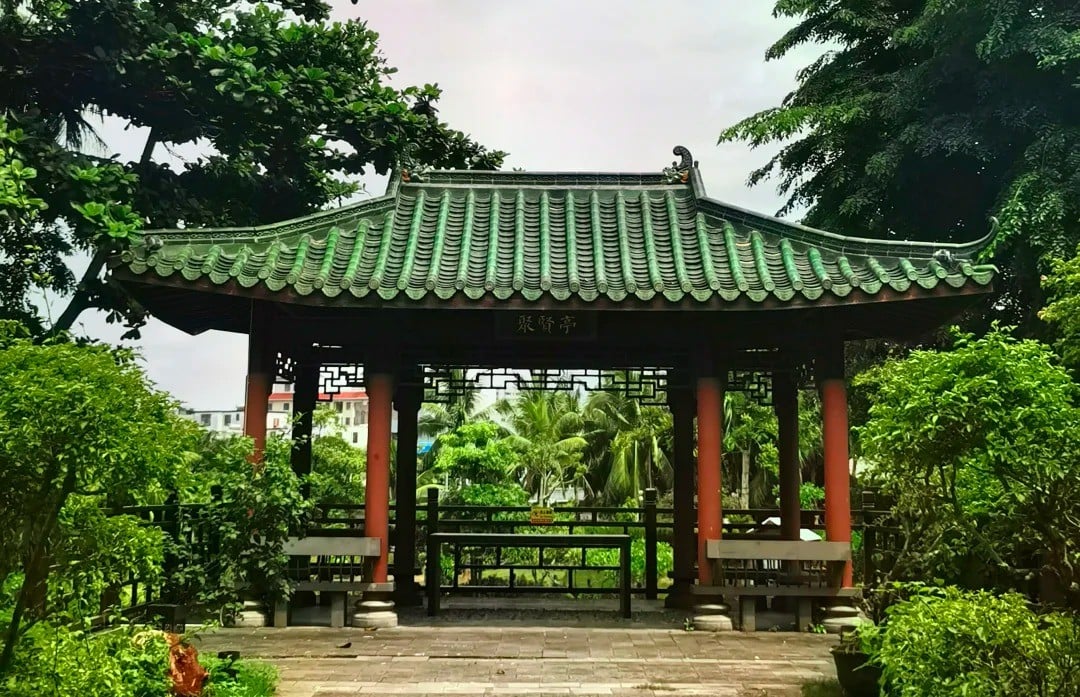 Temple of the Five Lords,Haikou,Hainan,Chinaexplorertour Traditional Chinese pavilion with a green-tiled roof and red pillars in a lush garden setting.