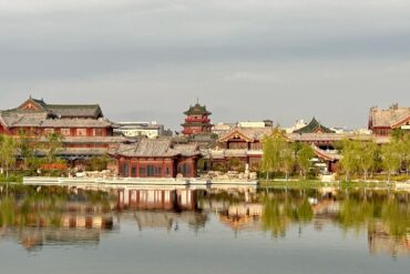 Baogong Lake & Park,Kaifeng,Henan,Chinatravel Traditional Chinese temple complex along a calm lake with reflections in the water and trees lining the shore.