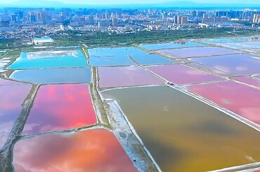 Aerial view of rainbow-colored salt evaporation ponds with a distant city skyline on the horizon.Salt Lake,Yuncheng, Shanxi