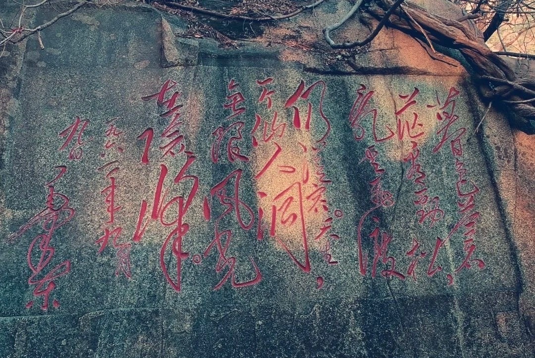 A scenic rock wall with traditional Chinese calligraphy inscriptions in red ink.