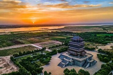 A multi-tier pagoda-style temple complex at sunset, surrounded by gardens and fields,Stork Tower,Yuncheng,Shanxi