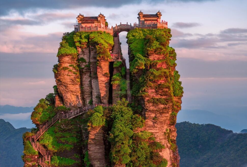 Tall rock pillar topped with traditional-style buildings, connected by stairways and lush greenery, overlooking a distant valley.Fanjing Mountain,Tongren,Guizhou