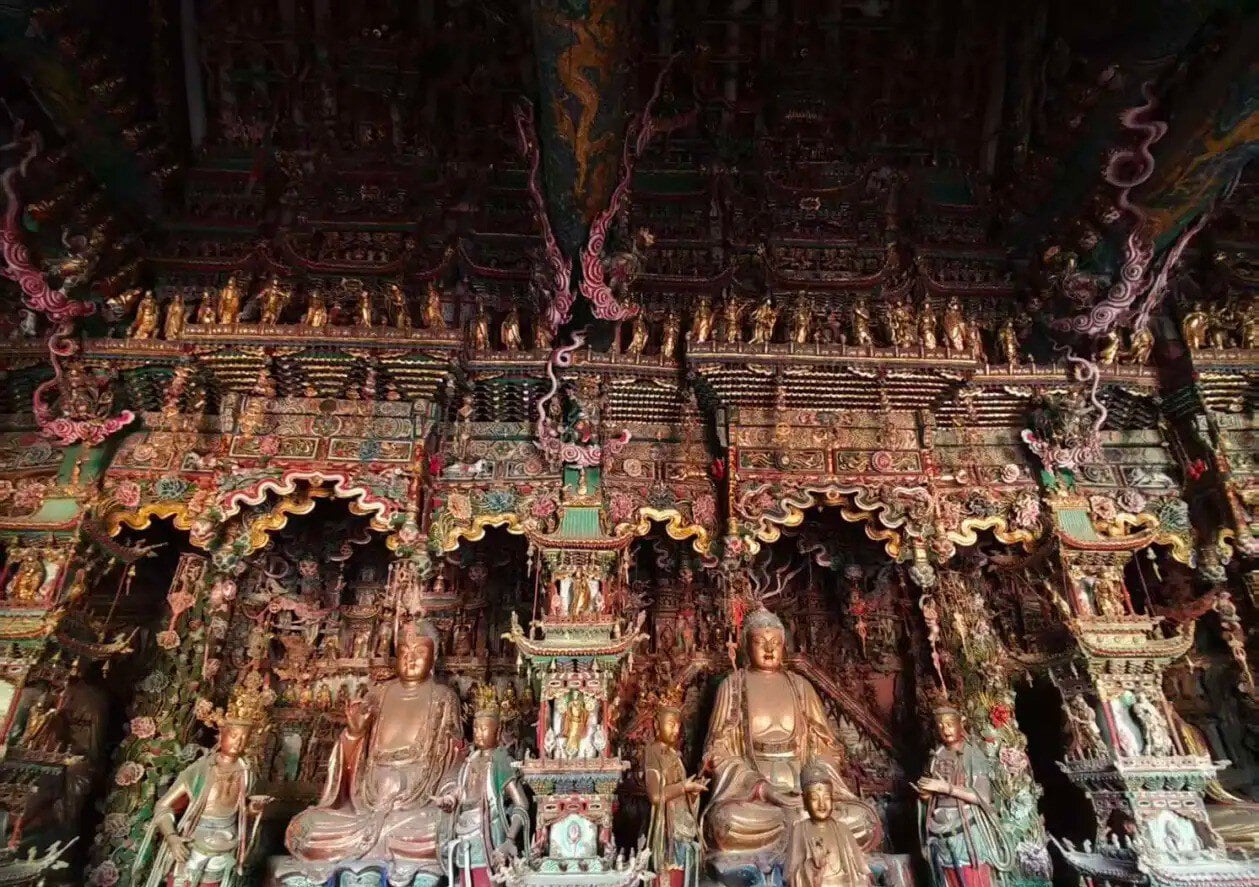 Intricately carved, colorful shrine with multiple Buddha statues inside a richly ornamented temple hall,Xiaoxitian Hanging Temple,Linfen,Shanxi