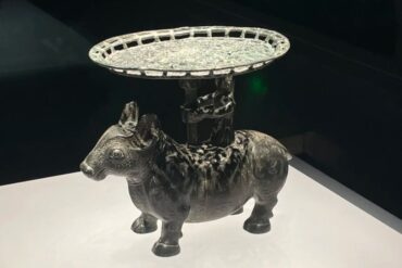 Decorative metal donkey statue with an ornate circular tray on its back, displayed on a white pedestal.Shanxi Museum,Taiyuan, Shanxi