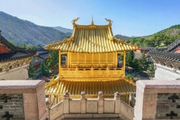 Golden pagoda-style temple pavilion with ornate roof, set among gray stone walls and surrounding hills in a Chinese temple complex,Xiantong Temple,Xinzhou,Shanxi,Chinatravel