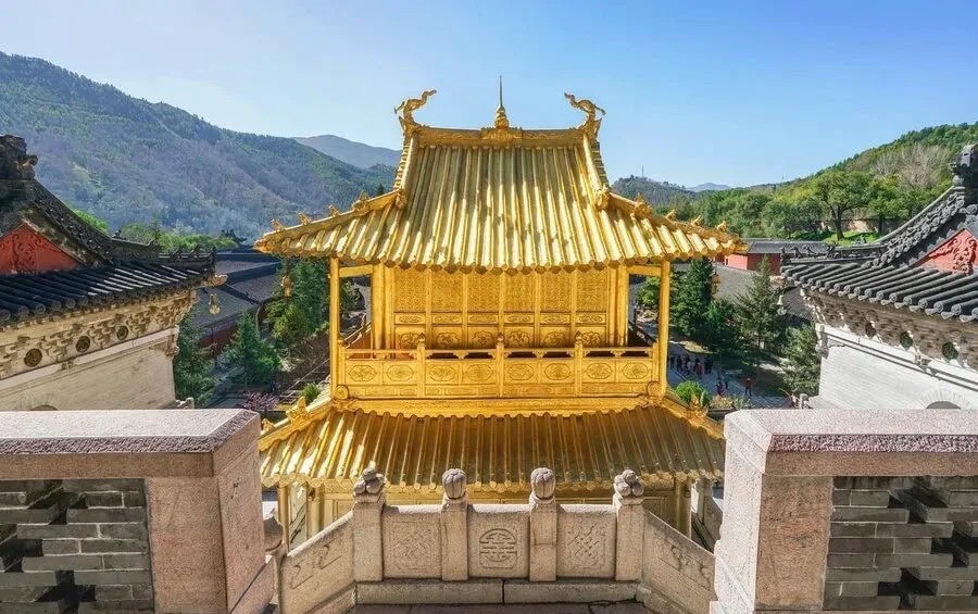 Golden pagoda-style temple pavilion with ornate roof, set among gray stone walls and surrounding hills in a Chinese temple complex,Xiantong Temple,Xinzhou,Shanxi,Chinatravel